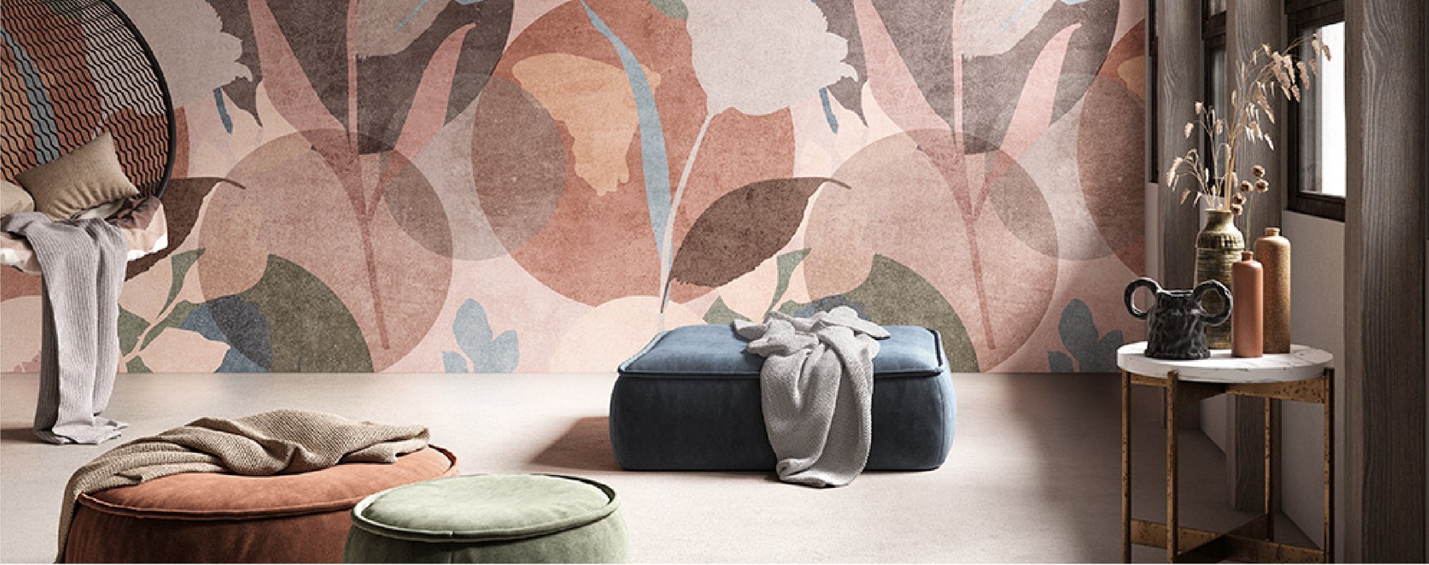 Pouf imbottito blu con un plaid grigio, davanti a una parete a grandi foglie