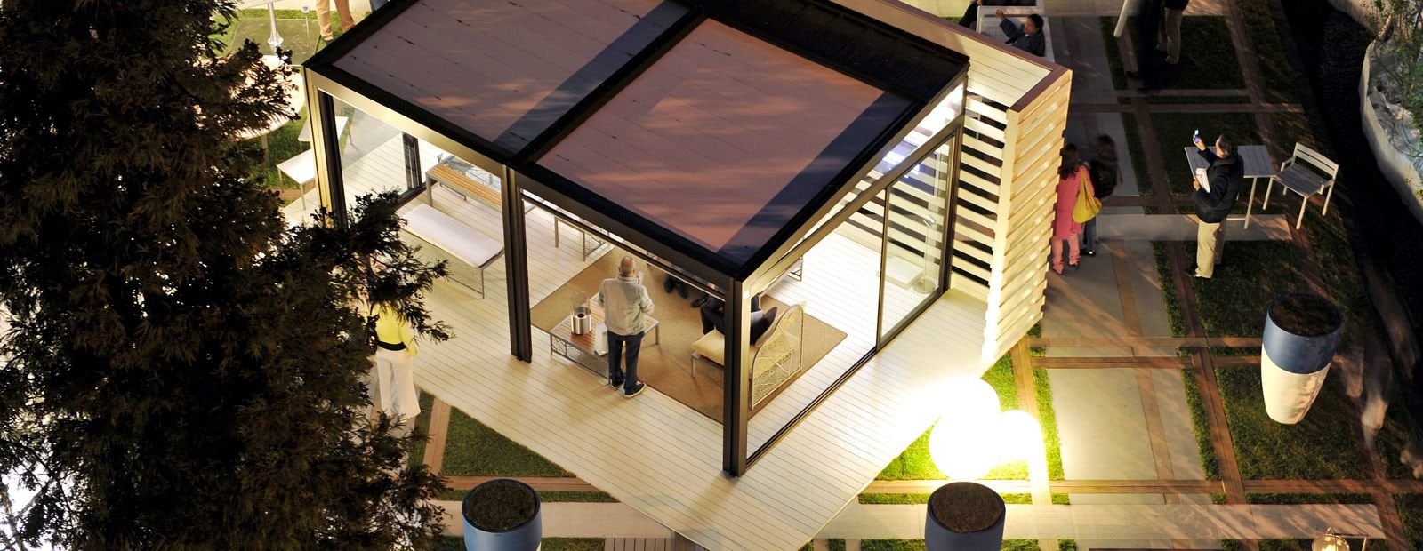 Pergola bioclimatica illuminata di sera in un giardino, vista dall’alto