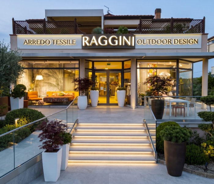 Ingresso dello showroom Raggini al tramonto, con le insegne Arredo tessile e Outdoor design