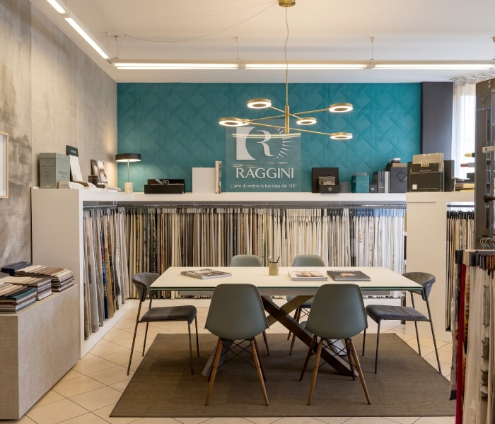 Interno dello showroom Home: tavolo da consulenza davanti ai campionari di tessuti