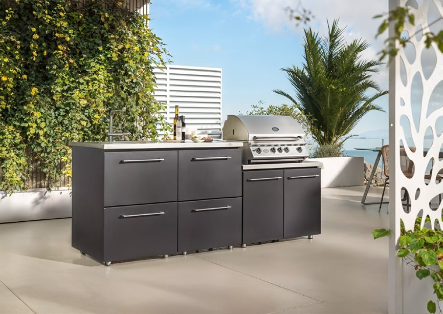 Cucina da esterno antracite con barbecue su una terrazza con piante e pannelli decorativi