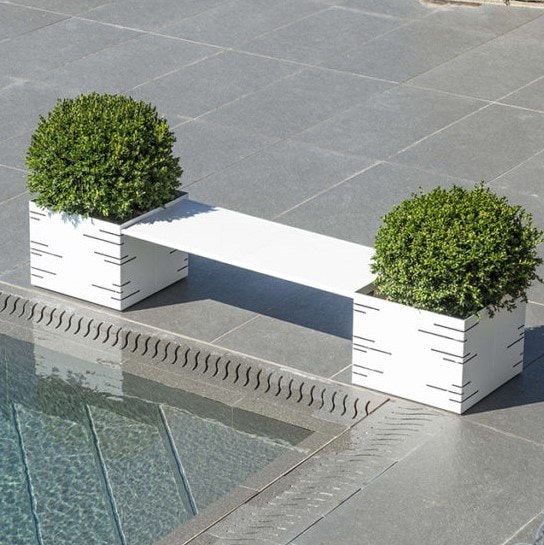 Fioriera Pot Panco: panchina bianca fra due fioriere modulari, accanto a una piscina