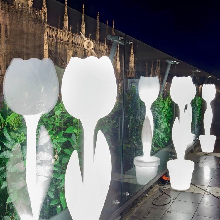 Lampade luminose a forma di tulipano davanti a una vetrata, di notte