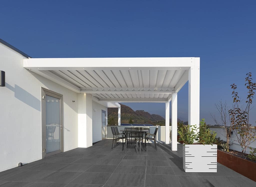 Pergola bianca su una terrazza, con una fioriera Pergo Potter accanto a una colonna