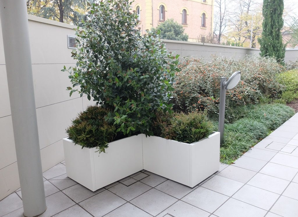 Fioriera Potter bianca ad angolo con arbusti, in un cortile