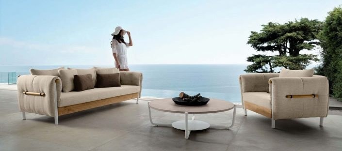 Divano e poltrona imbottiti con tavolino tondo su una terrazza vista mare