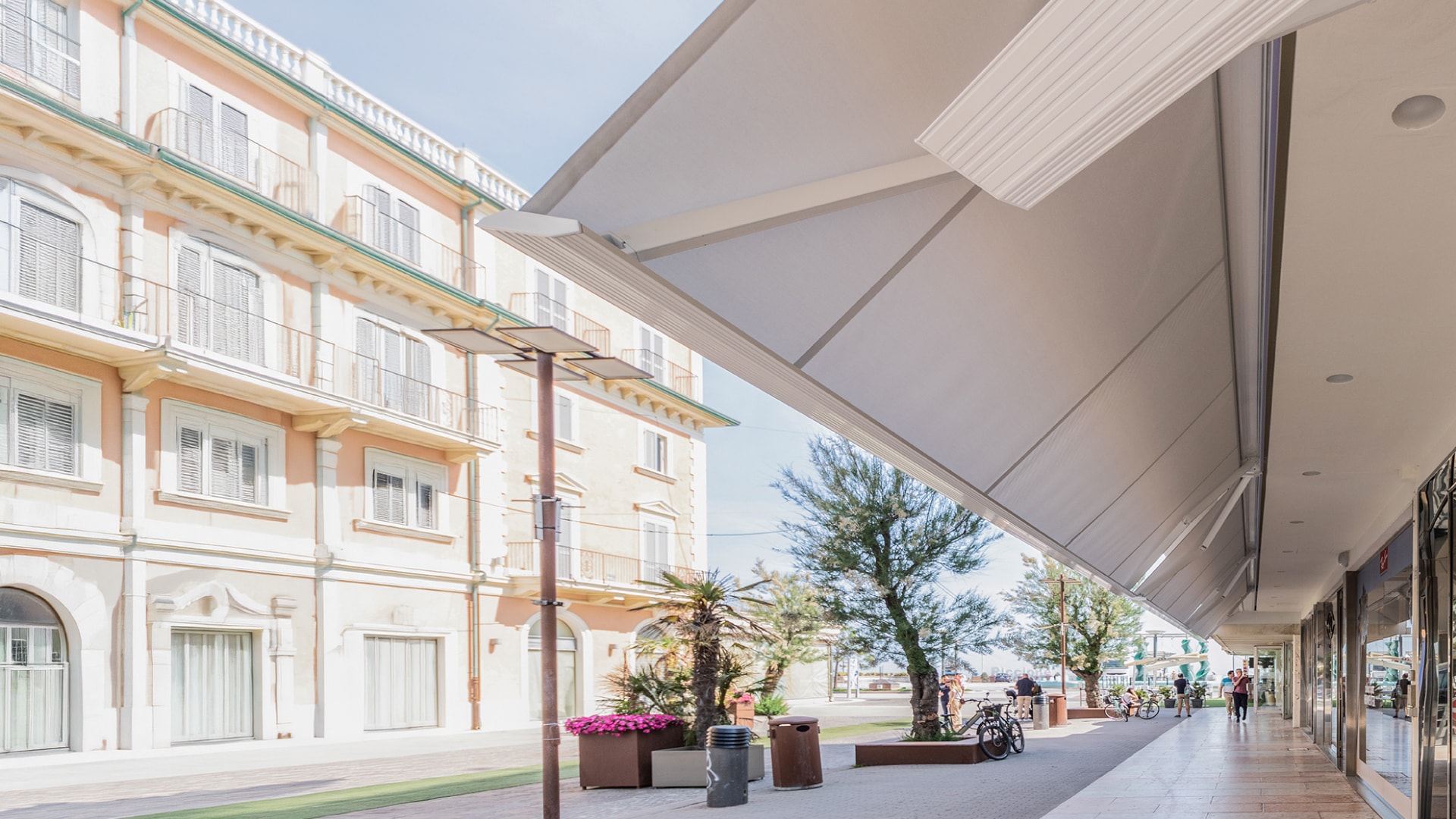 Tenda da sole a bracci bianca aperta sopra le vetrine di una via pedonale