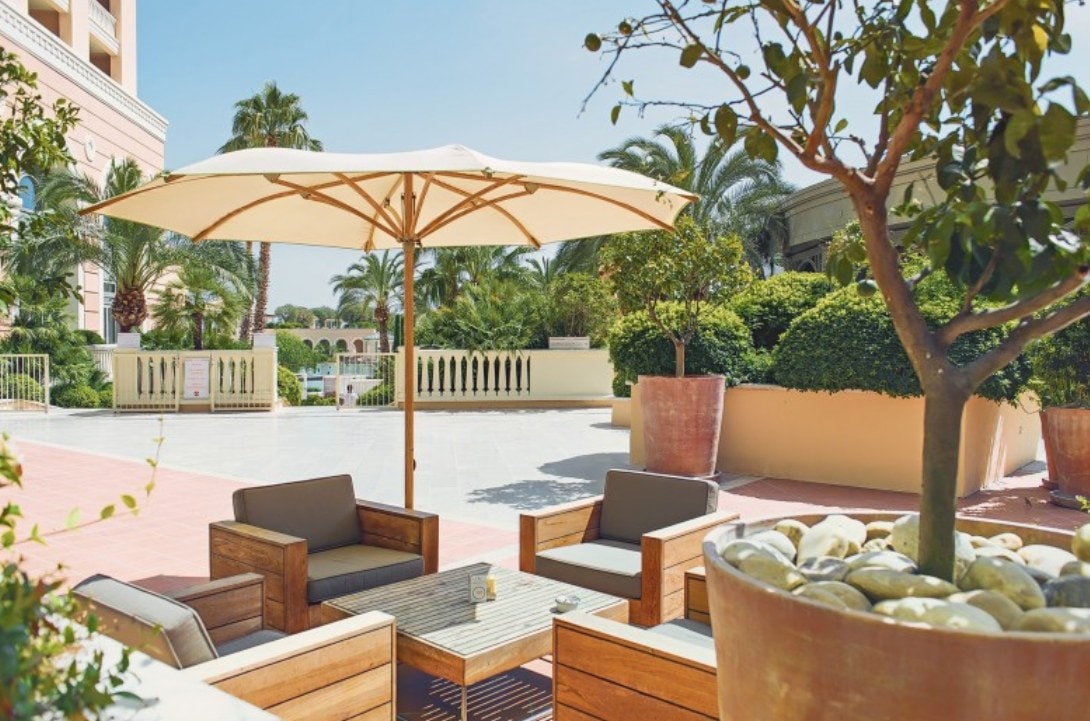 Ombrellone Bay sopra un salotto in legno nel giardino di un hotel