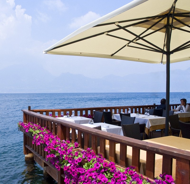 Ombrellone Dehor su una terrazza fiorita affacciata sul lago