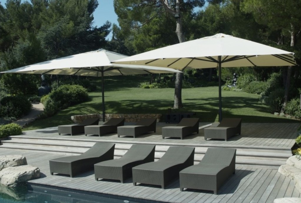 Ombrelloni Magnum sopra i lettini di una piscina in un parco