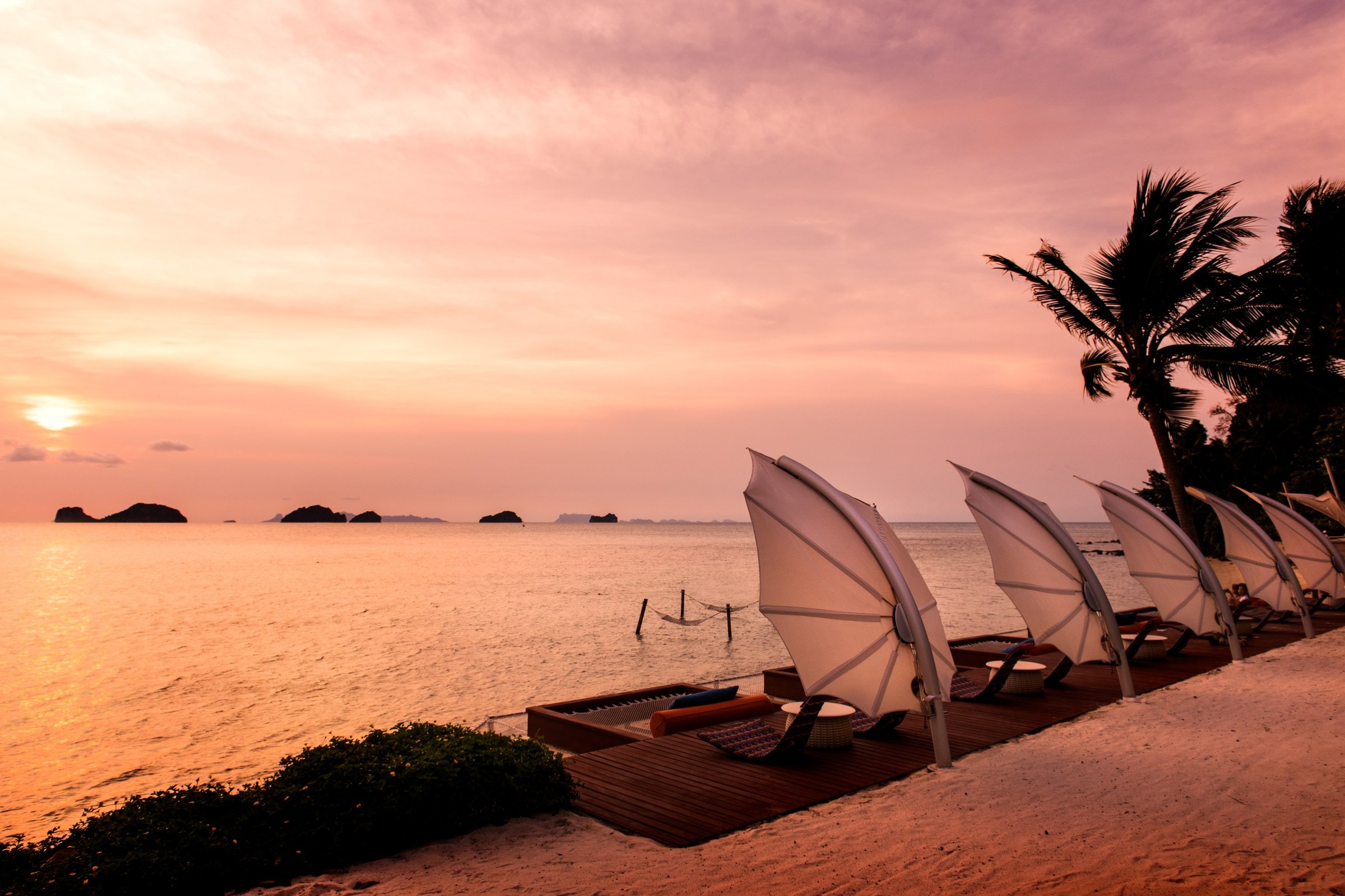 Ombrelloni Icarus su una spiaggia affacciata sul mare, al tramonto