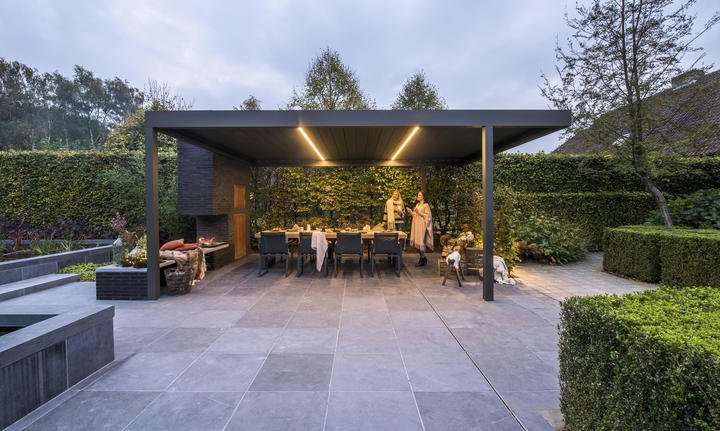 Pergola Algarve illuminata la sera su una terrazza in pietra, con tavola apparecchiata