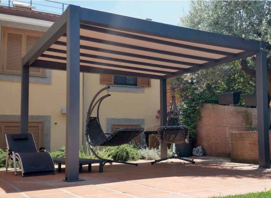 Pergola Flat Harmony antracite con poltrona sospesa, accanto a una casa