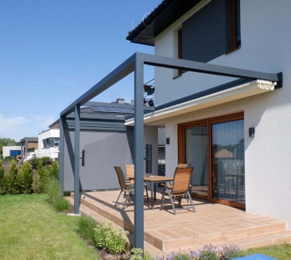 Pergola Olympia grigia addossata a una casa, con tavolo sulla pedana