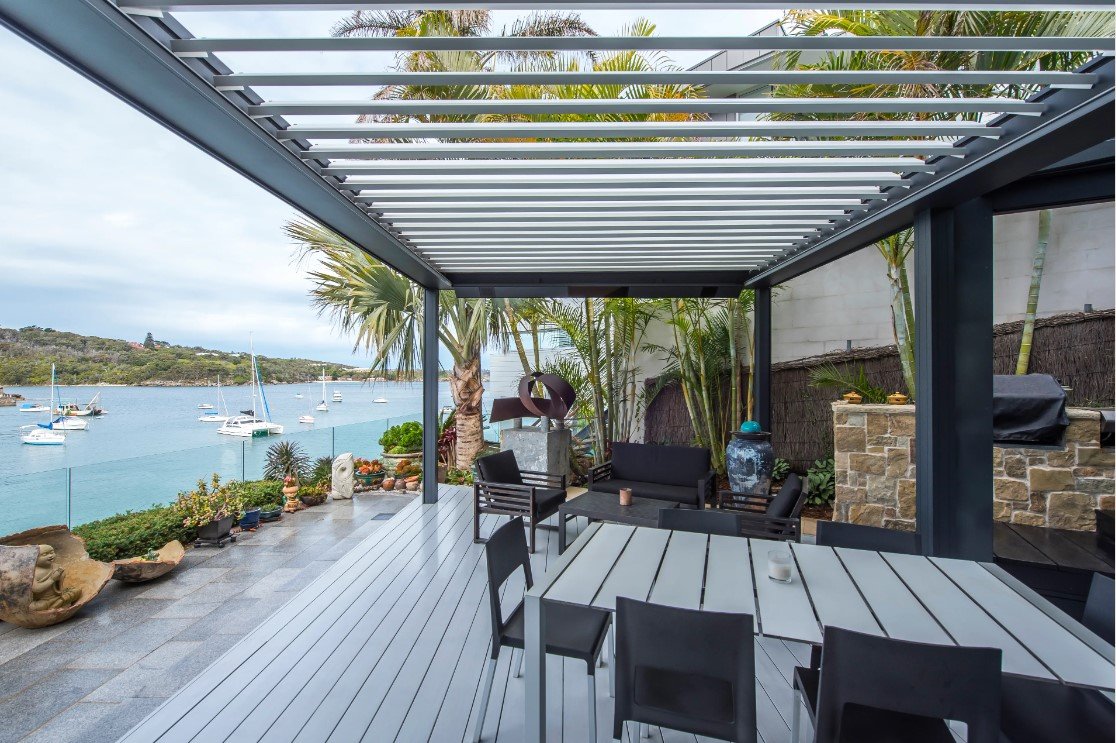Terrazza sul mare coperta da una pergola Skye con lamelle aperte