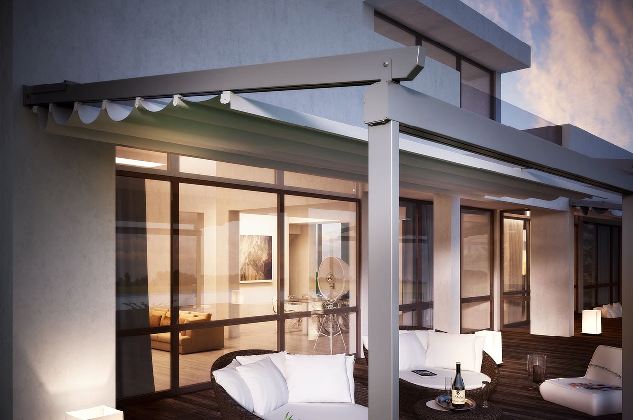 Pergola Sunrise addossata a una casa moderna, con salotto illuminato