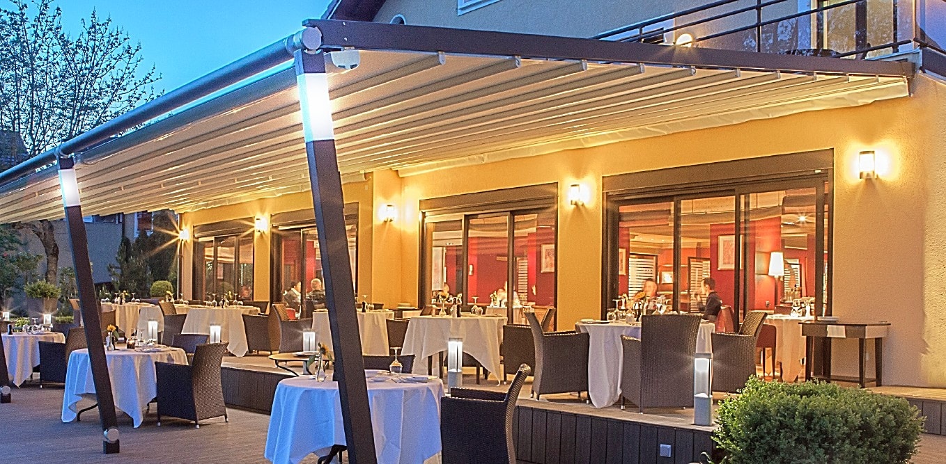 Pergotenda con luci accese sopra il dehors di un ristorante, di sera