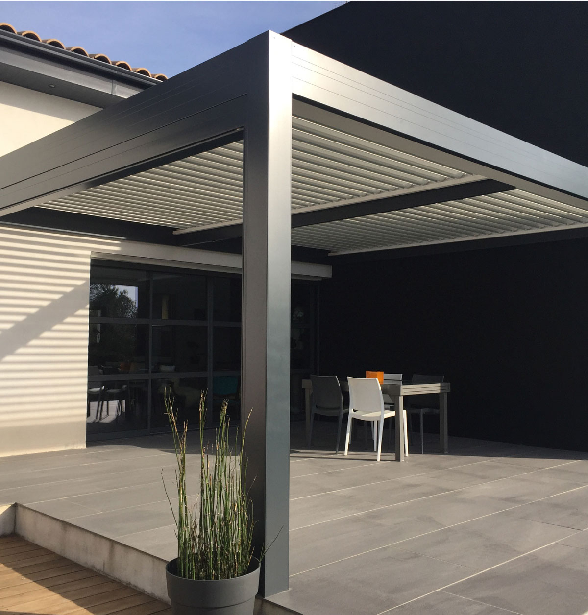 Pergola Zefiro antracite su un patio con tavolo