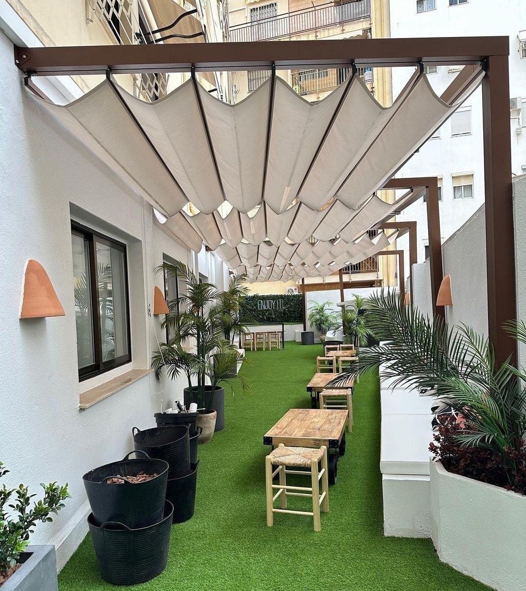 Cortile con prato sintetico e tavolini sotto un tendalino Elite Dream
