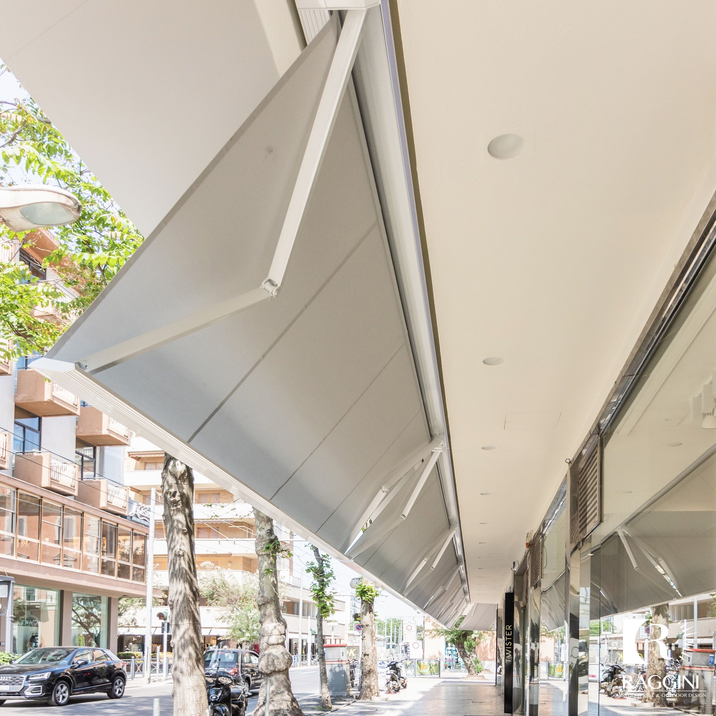 Tende Flat Plus bianche lungo le vetrine di un porticato in città