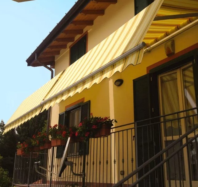 Tende Grandangolo a righe gialle sui balconi di una casa gialla