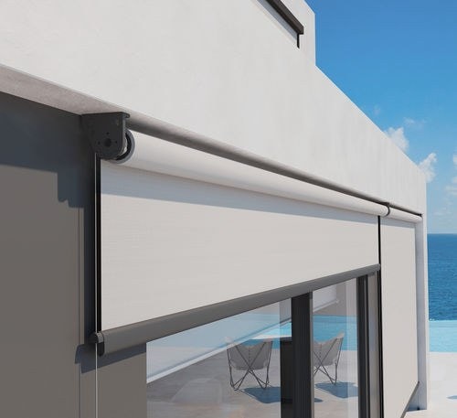 Tenda a caduta Helios con cassonetto tondo su una vetrata vista mare