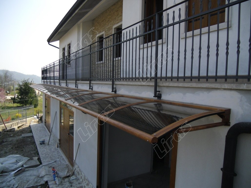 Lunga pensilina a curve color legno sotto una balconata