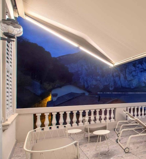 Tenda Spring con LED accesi su un balcone affacciato sulla scogliera, di sera