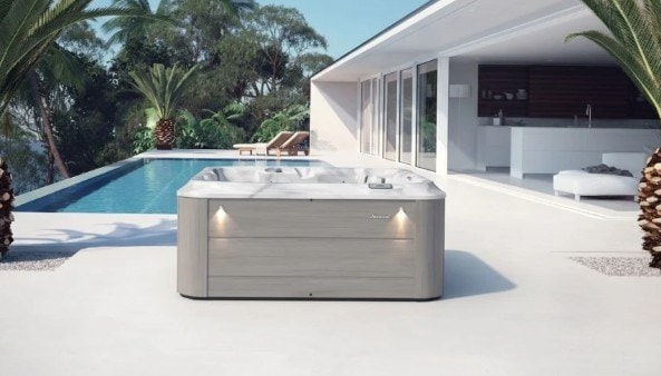 Spa J-235 su una terrazza bianca accanto a una piscina, fra le palme