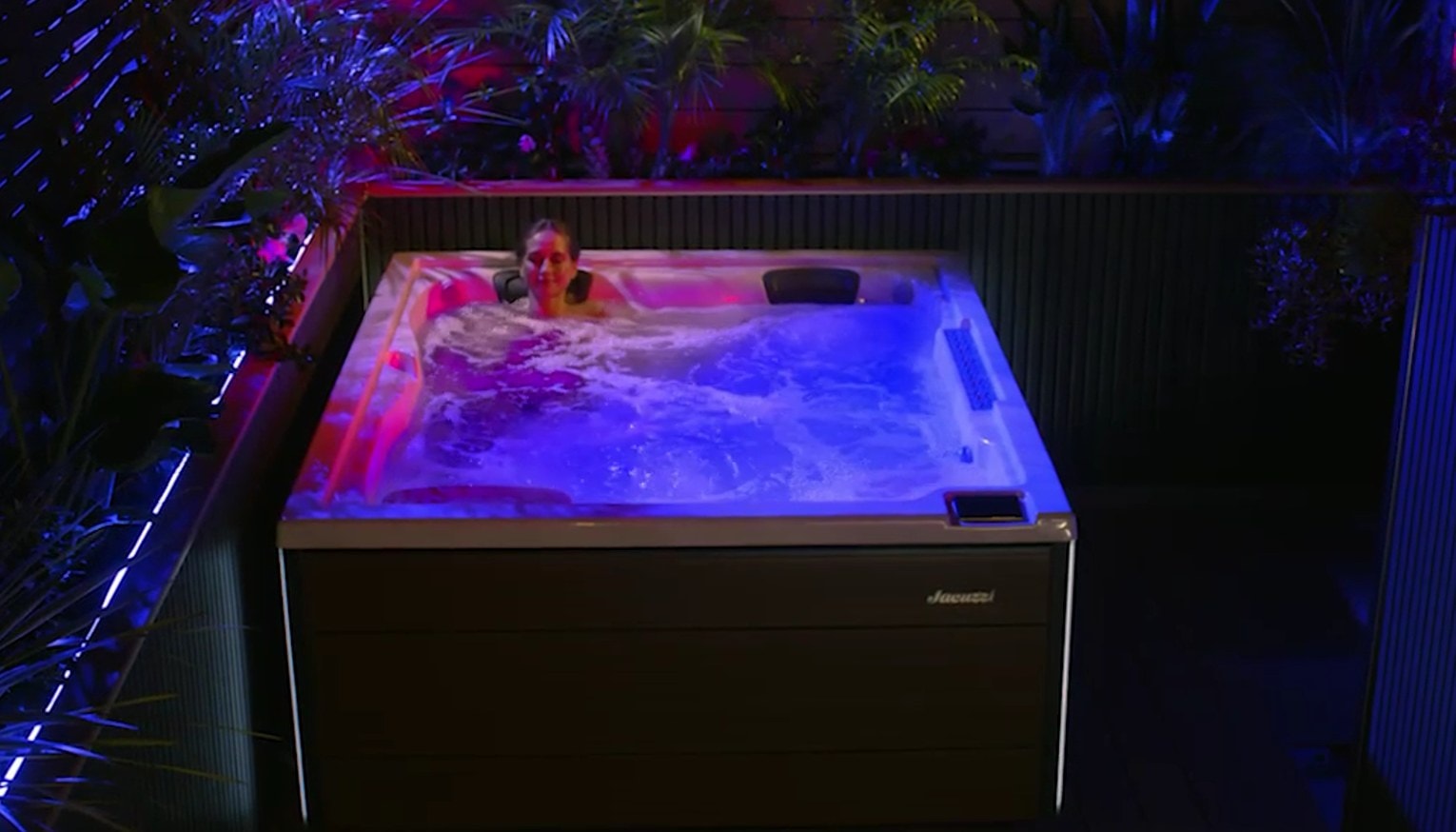 Spa J-404L illuminata di rosa e blu su una terrazza, di sera