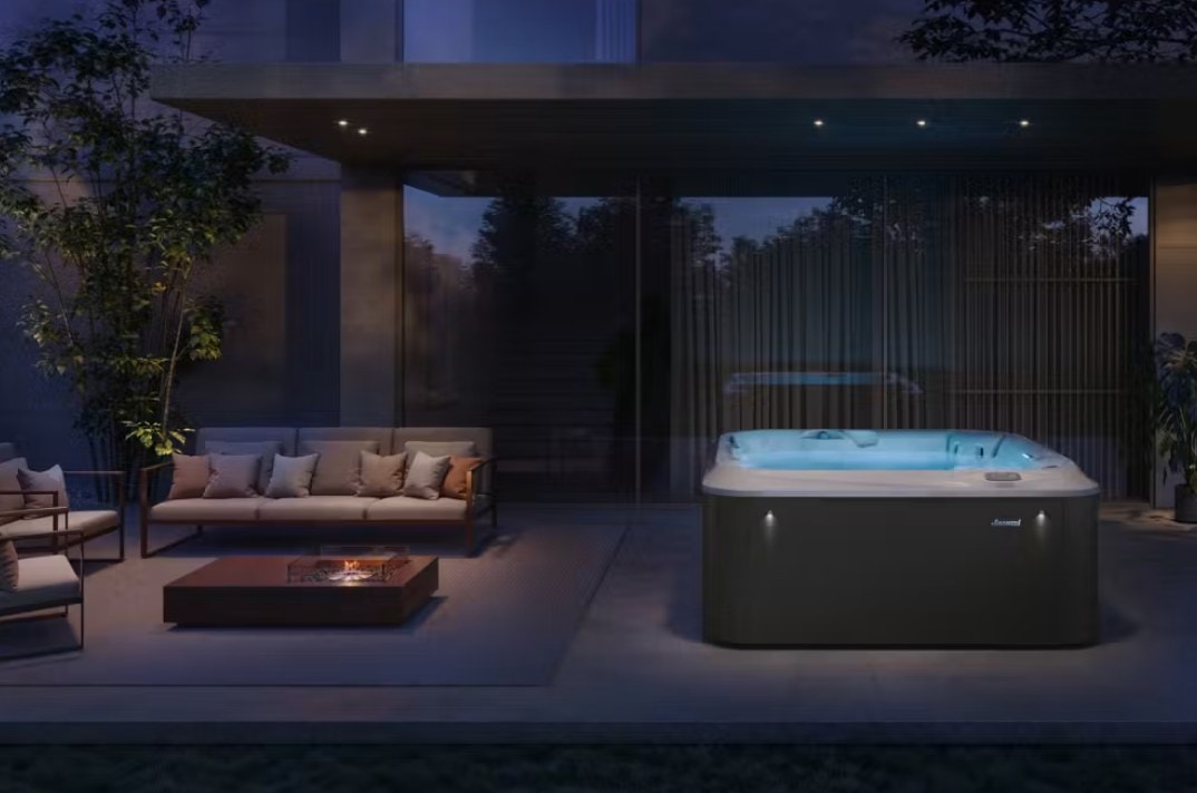 Spa Omnia illuminata sotto una pergola, accanto a un salotto esterno, di sera