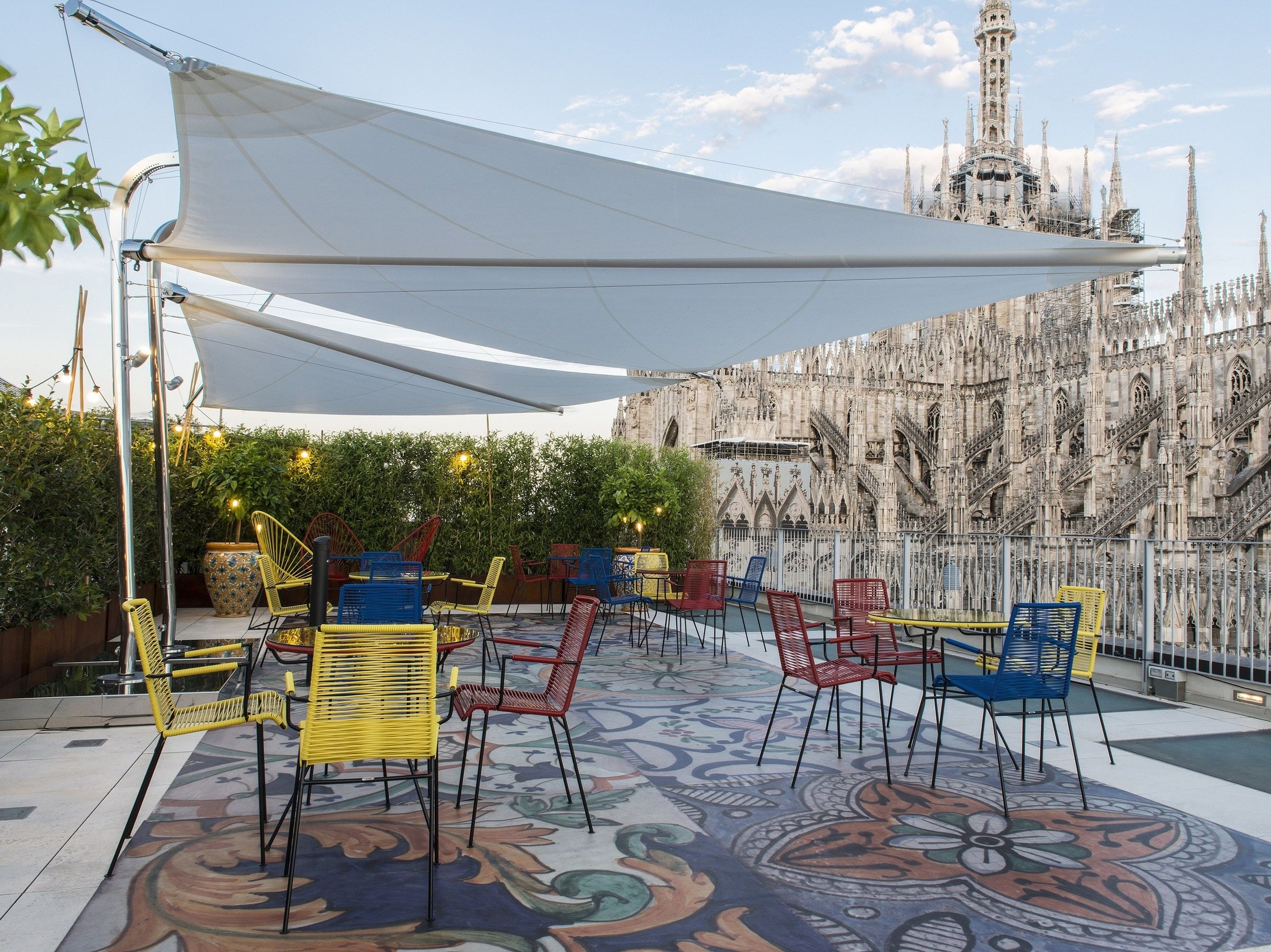 Vele Ponente sopra un dehors con sedie colorate, davanti al Duomo di Milano