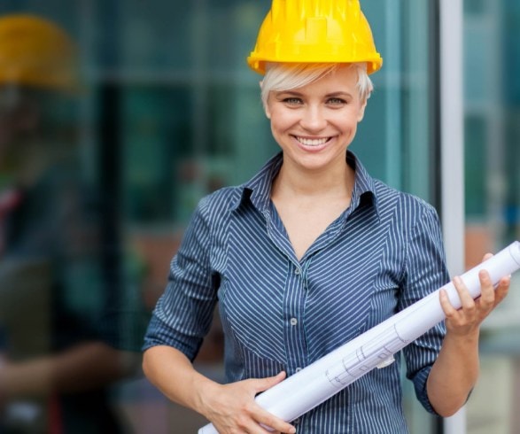 Progettista con il casco e i disegni davanti a una vetrata