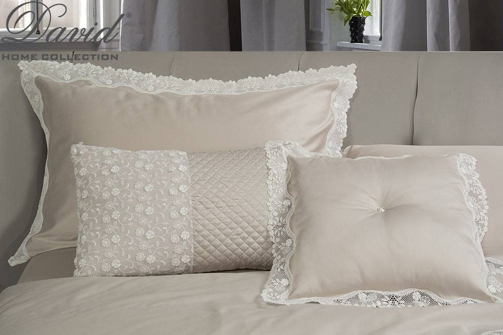 Cuscini beige con ricami e balze sopra un letto bianco