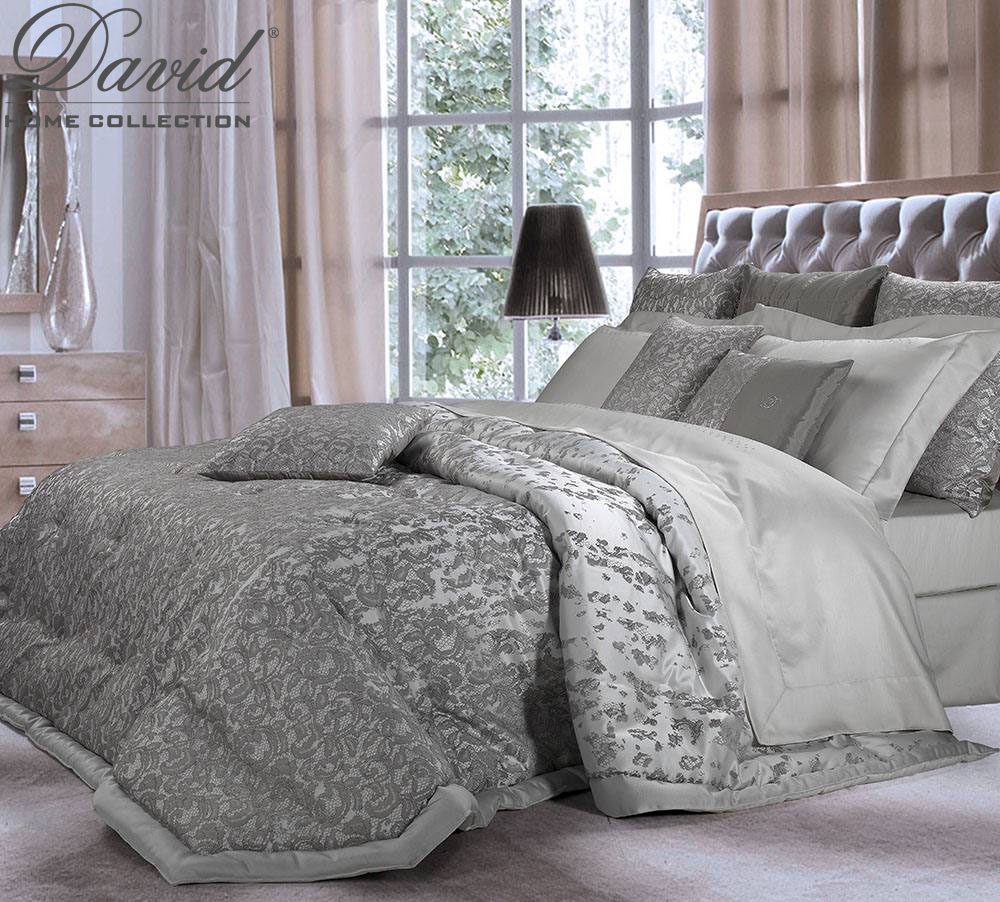 Letto con piumone damascato grigio e cuscini in raso, in una camera classica
