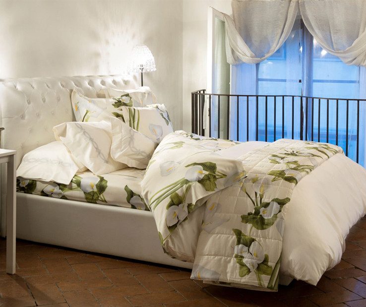 Letto con piumone a fiori verdi davanti a una finestra luminosa