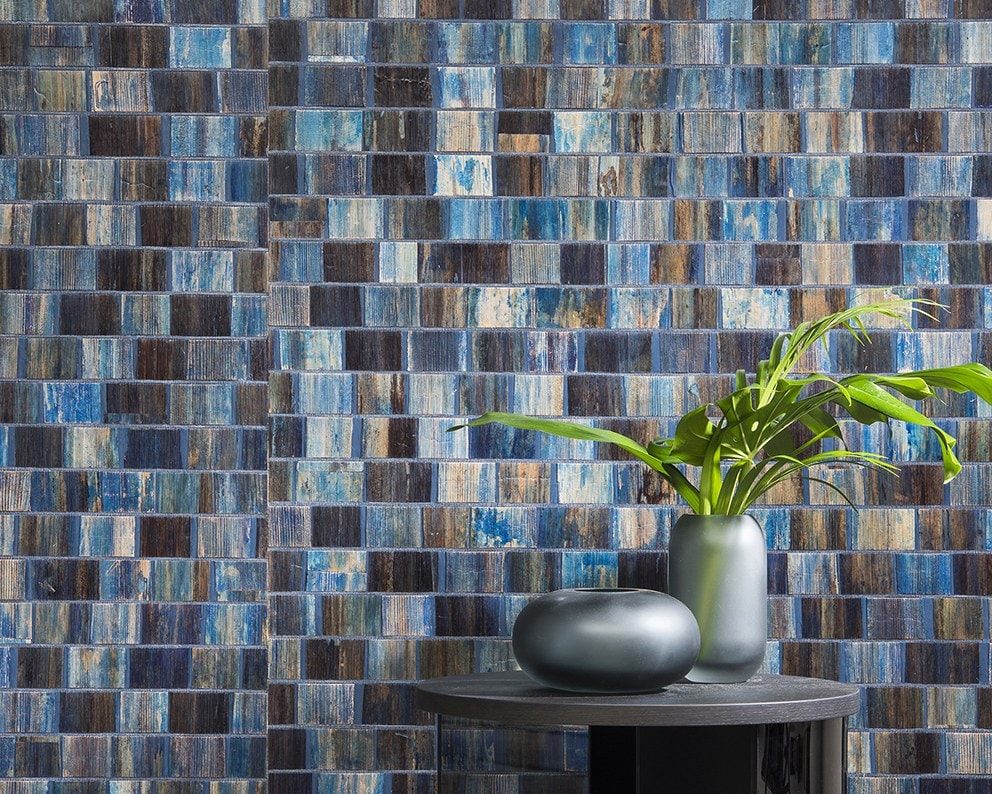 Tavolino tondo scuro con vaso e centrotavola davanti a una parete a mosaico blu
