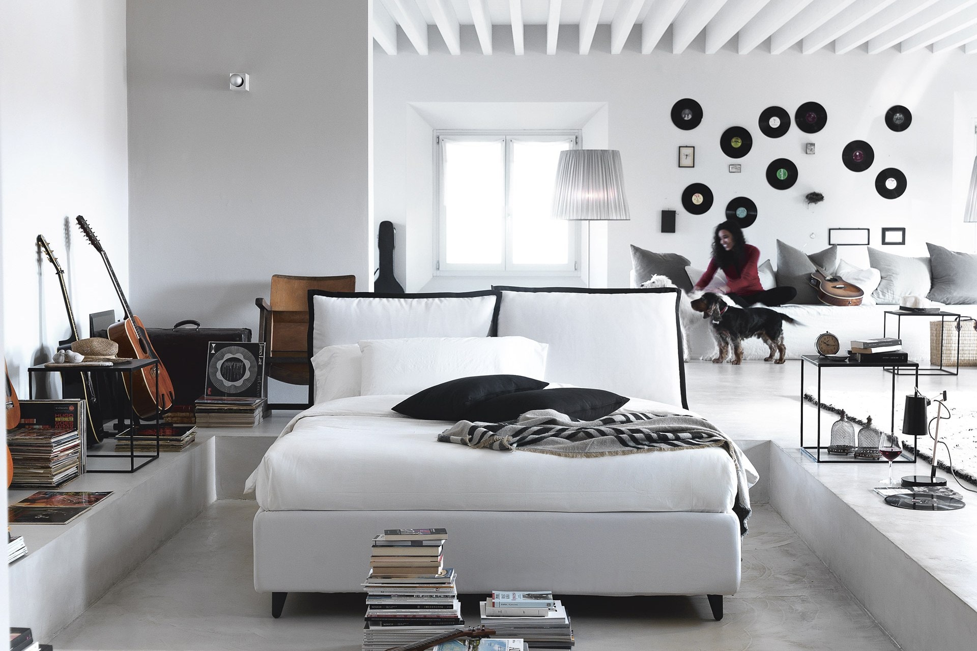 Letto imbottito bianco in un loft con parete di orologi