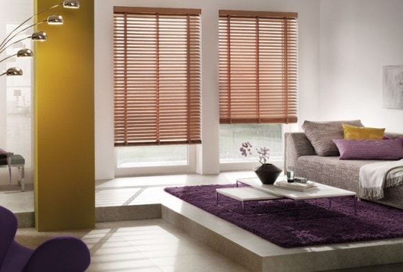Open space con parete gialla, tappeto viola e veneziane in legno