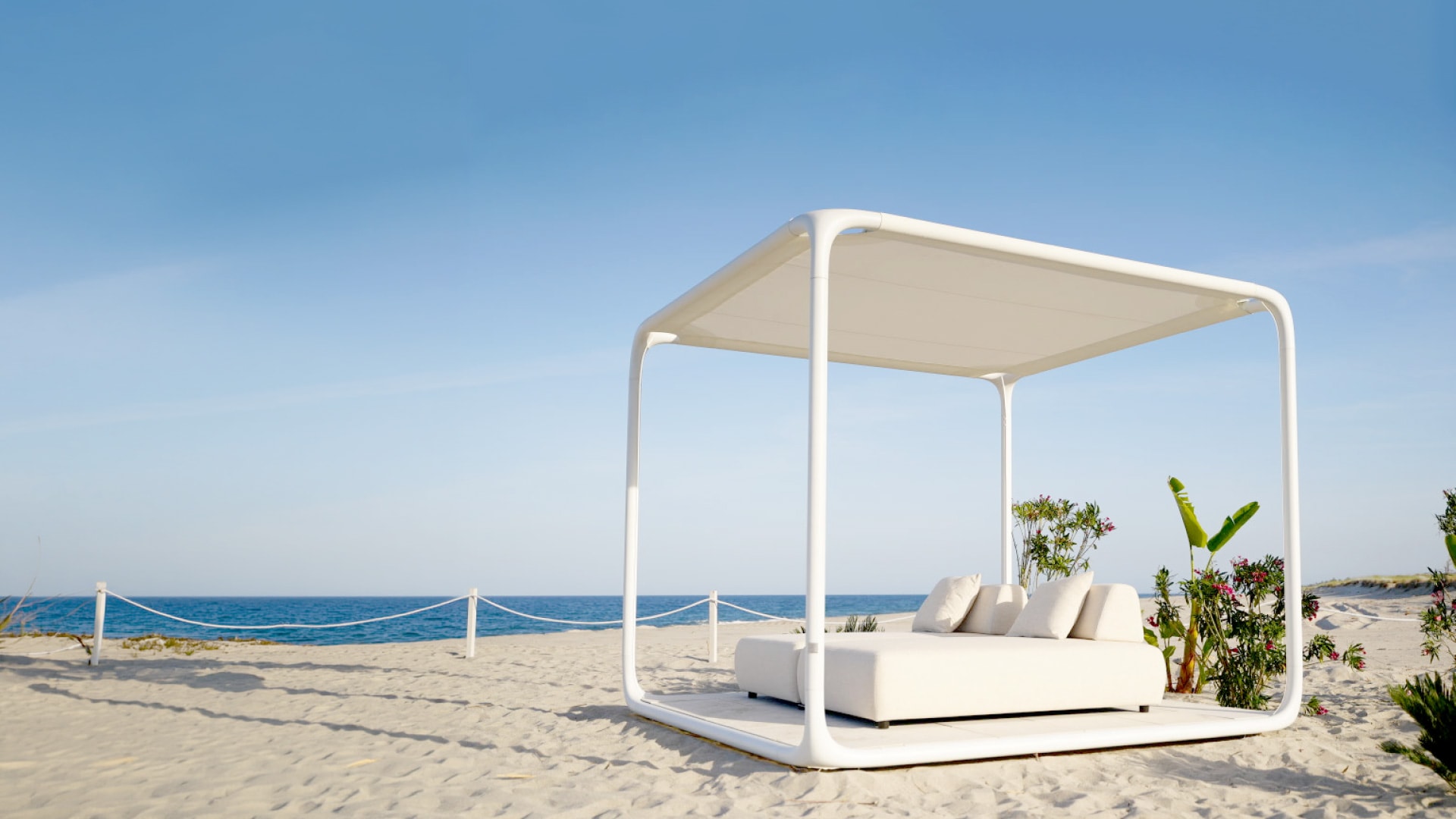 Gazebo 2.0 bianco con divano sulla sabbia, davanti al mare