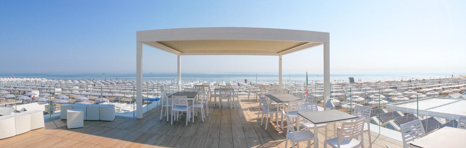Pergotenda bianca sulla terrazza dei Bagni Mario 65, con la spiaggia di Riccione sullo sfondo