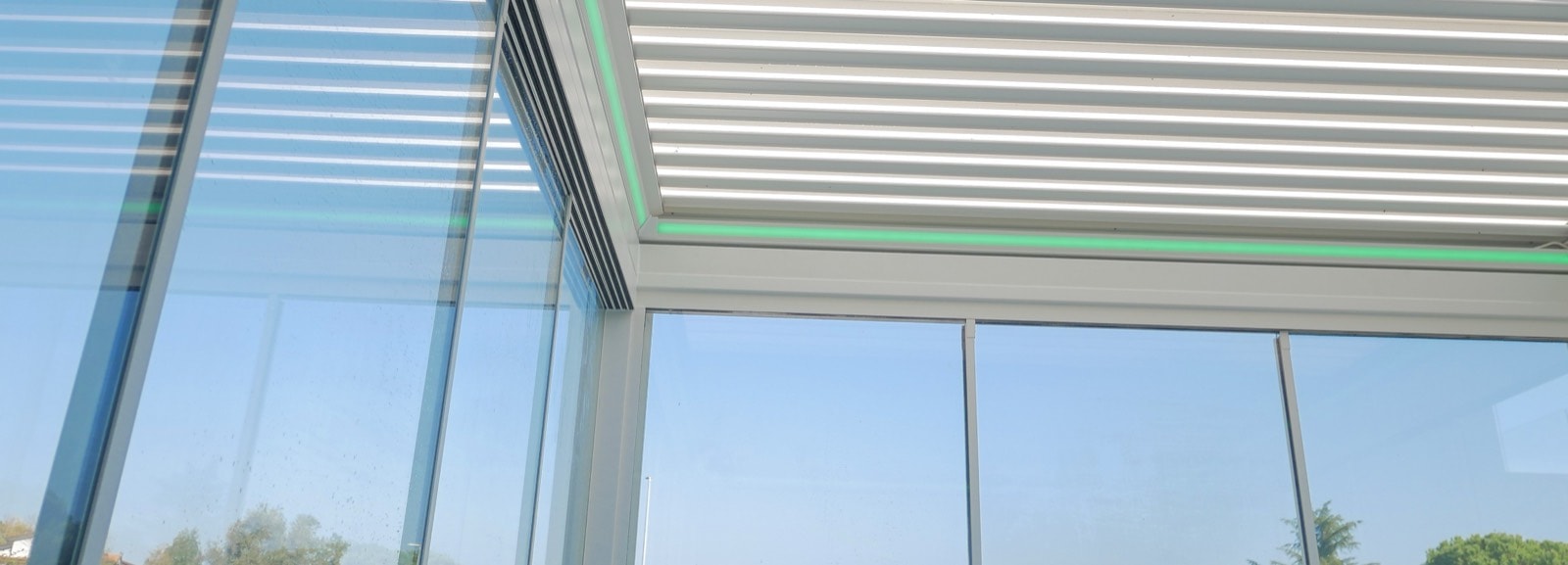 Pergola bioclimatica bianca con lamelle retrattili e vetrate scorrevoli su una terrazza
