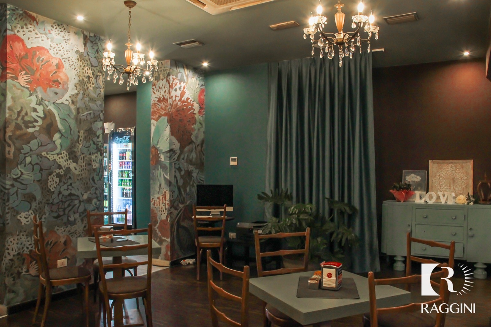 Tavoli quadrati e sedie in legno sotto un lampadario di cristallo, in un caffè