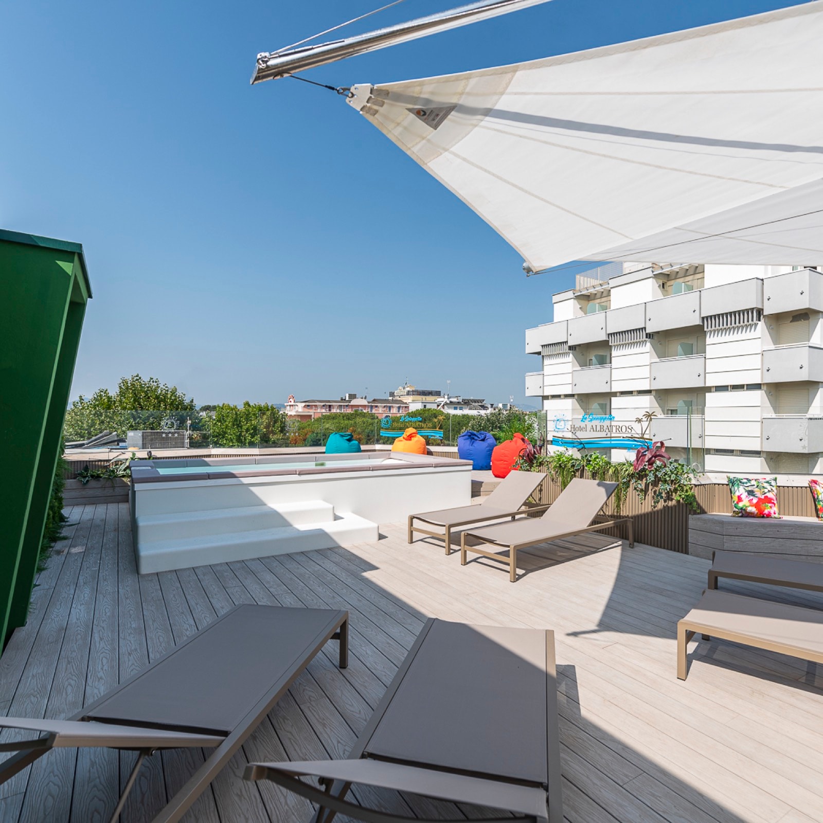Lettini e pouf colorati sul rooftop dell’Hotel Albatros, sotto la vela