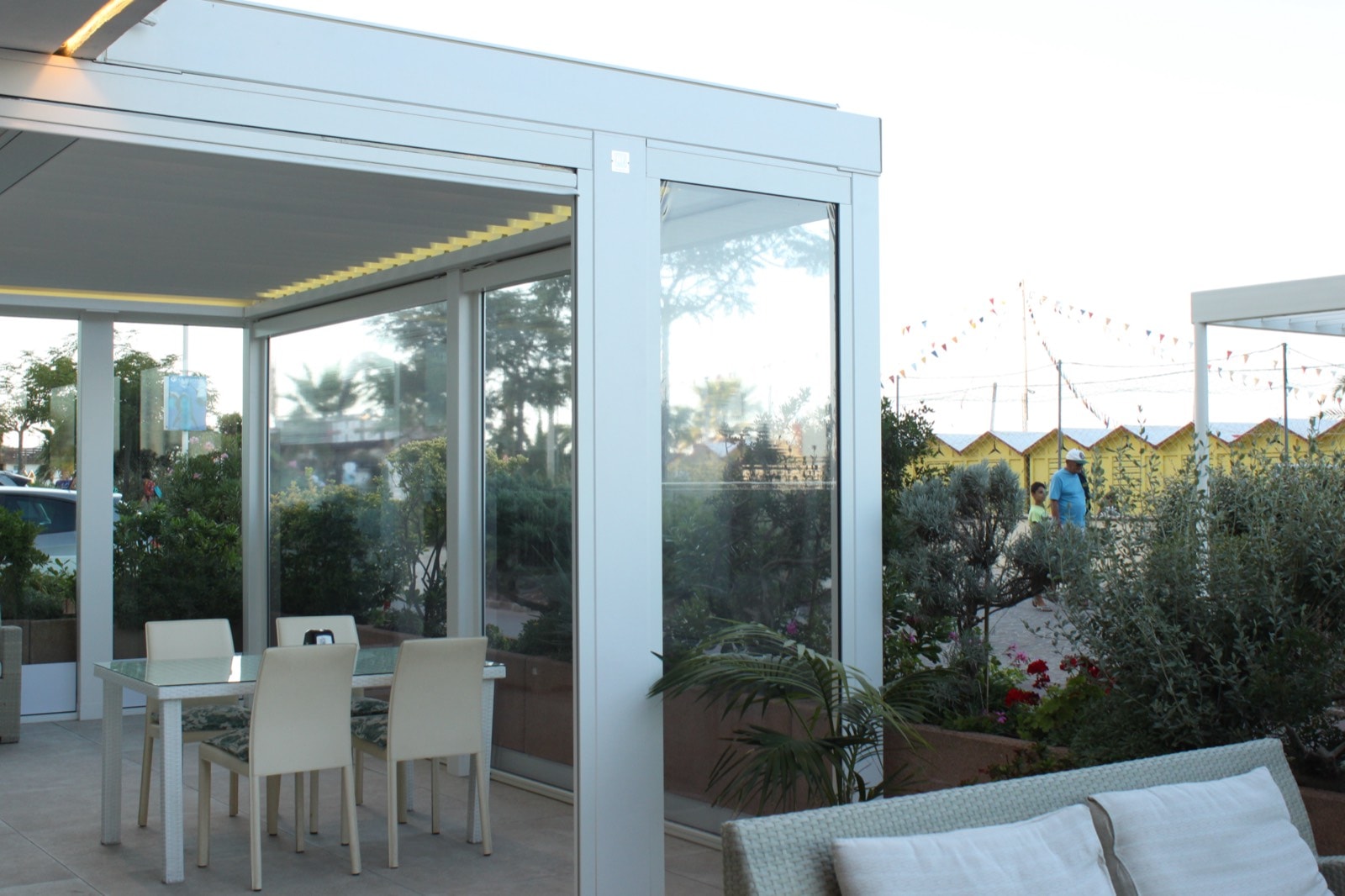 Pergola bioclimatica bianca con chiusure in vetro davanti all'Hotel Des Nations