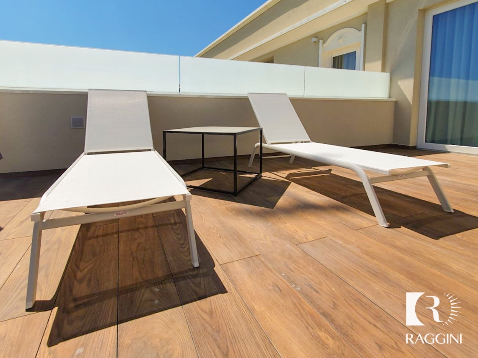 Due lettini bianchi sulla terrazza in legno della suite dell’Hotel Litoraneo
