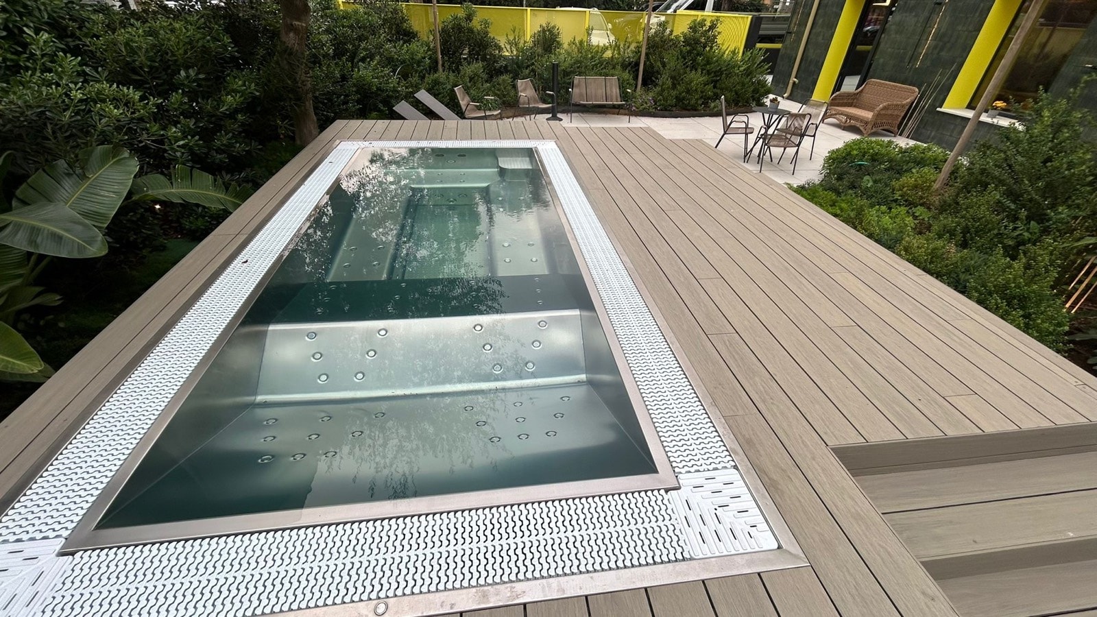 Piscina del Mode Eco Mood Hotel circondata da una pedana in WPC chiaro e dal verde