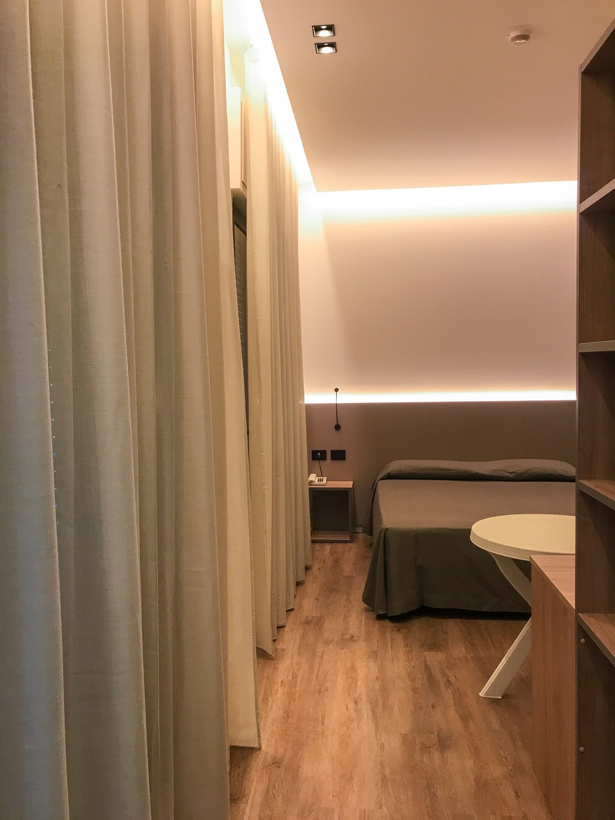 Camera dell’Hotel Renzo con tendaggi effetto lino e luce indiretta