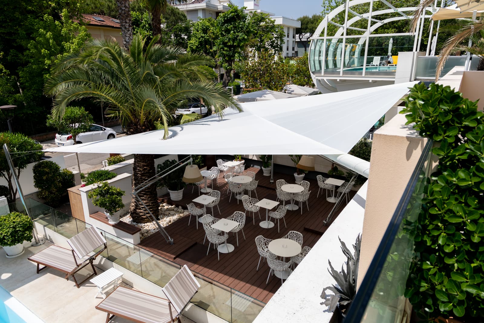 Terrazza dell'Hotel Select vista dall'alto: la vela bianca ombreggia i tavoli sulla pavimentazione in legno