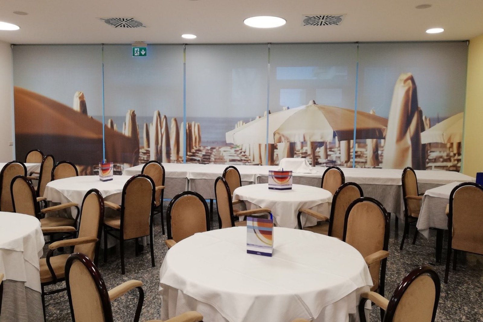 Sala da pranzo dell'Hotel Vittoria con tende a rullo stampate con immagini della spiaggia